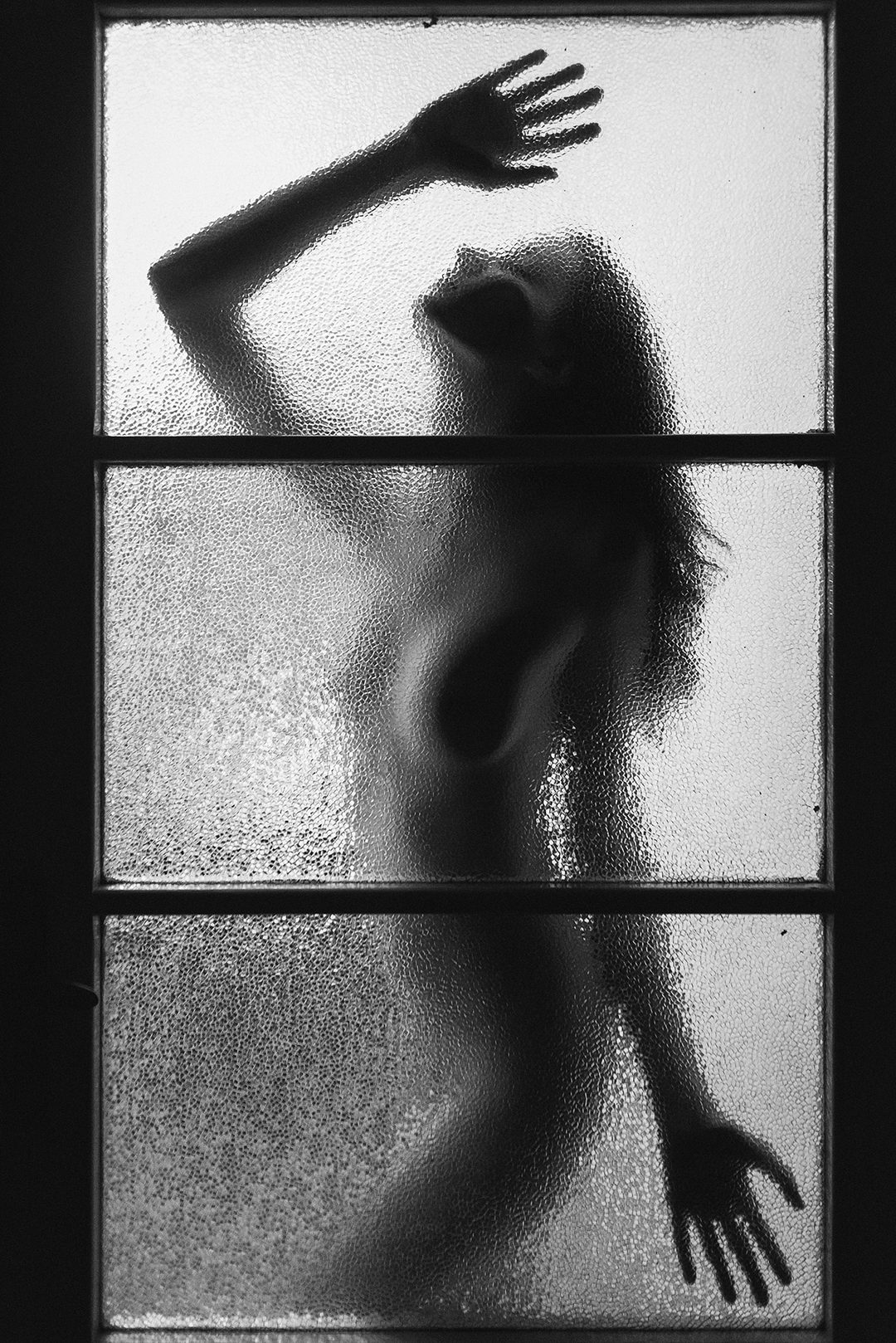 Night in Prague: Silhouette der Modelin Michaela hinter einer Tür mit strukturiertem Glas in Prag, Tschechien.